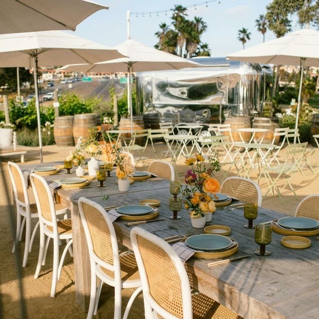 Patio set for a celebration with umbrellas, bistro seating, and the Moonlight Bar trailer